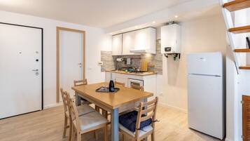 A compact kitchen with a dining table, chairs, a refrigerator, and a built-in oven.