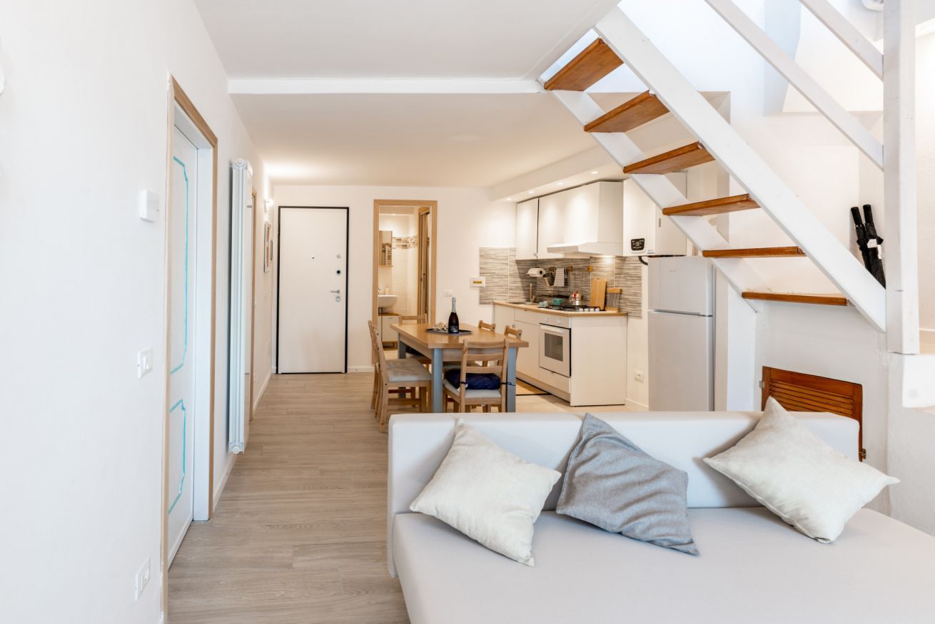 A modern interior with a sofa, dining table, and kitchen area.