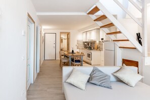 Ein modernes Interieur mit einer Couch, einem Esstisch und einer Küchenzeile.