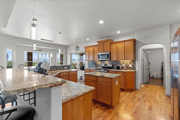 A modern kitchen with granite countertops, wooden cabinets, and stainless steel appliances.