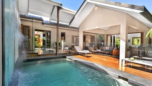 A modern pool area with a hot tub, lounge chairs, and a wooden deck. - Figtree Villas Palm Cove (Palm Cove)