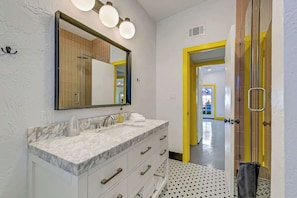 Un baño con lavamanos doble, un espejo grande y cabina de ducha.