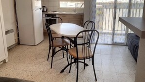 Eine kleine Küche mit Esstisch und Stühlen, einem Kühlschrank und einem Fenster mit Blick.
