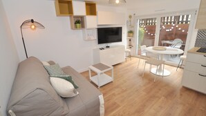 Una sala de estar moderna con sofá, televisor y comedor.