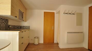 Eine Küche mit Holzausbau, einer Fliesenküchenrückwand, einer Holztür und einem an der Wand befestigten Heizkörper.