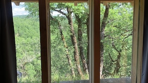 A wooden cabin with a view of a forested landscape through a window. - L'Hermitage, an old stone shepherd's hut (Salvagnac-Cajarc)