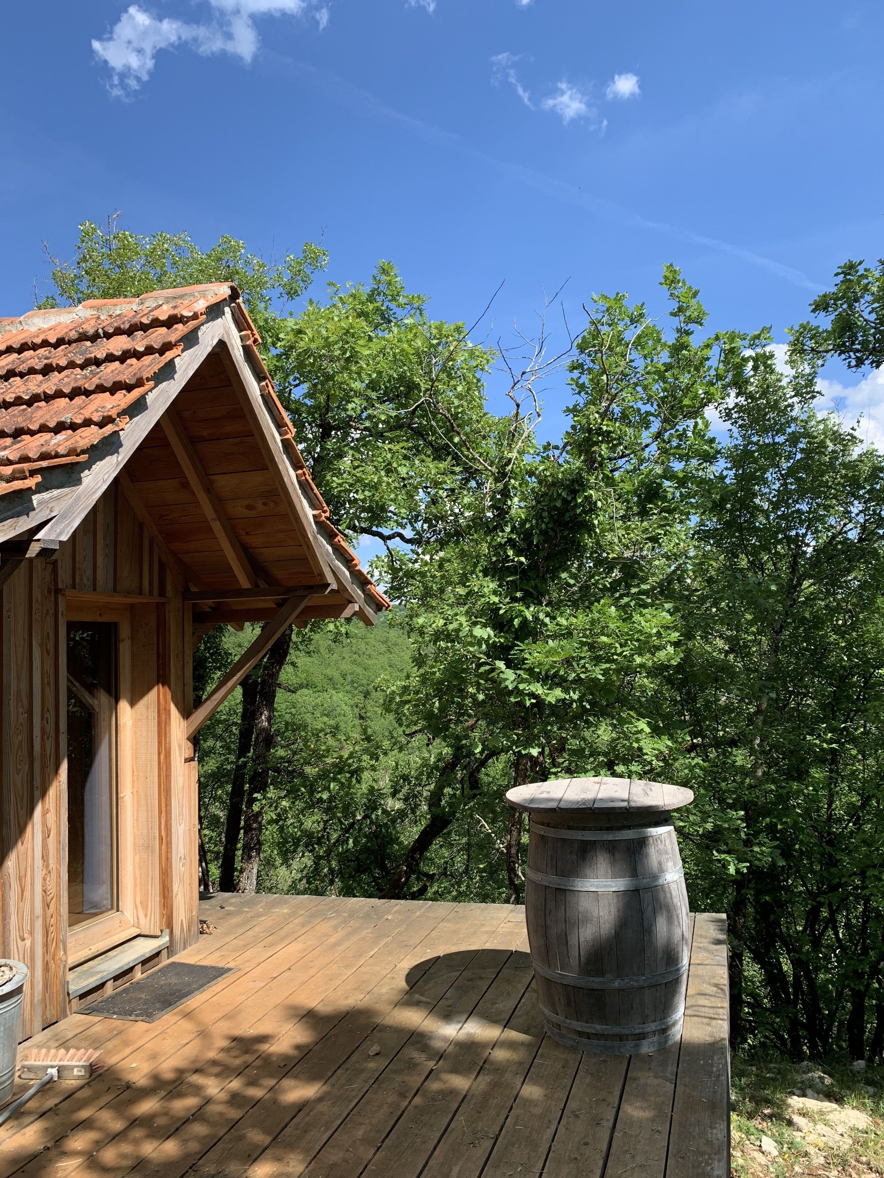 A wooden cabin with a tiled roof and a large barrel on the deck.