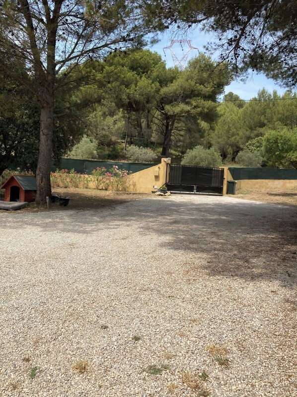 A gravel area with a small doghouse, a fenced enclosure, and a green wall in the background. - Villa with Private Pool + Spa Included – Provence (salon de provence)