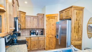 Una cocina con armarios de madera, electrodomésticos de acero inoxidable y encimera de granito.