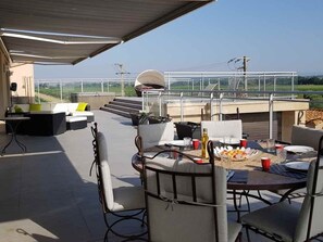 Une terrasse extérieure avec une table ronde, des chaises et un espace salon abrité.