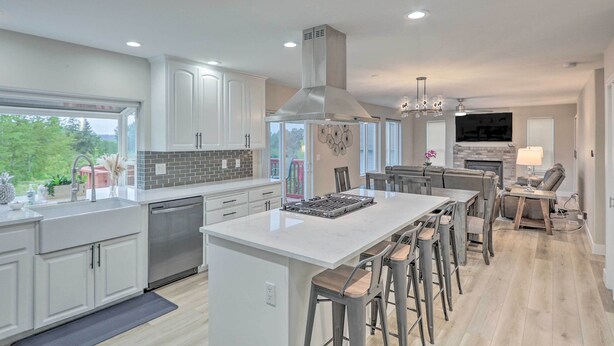 A modern kitchen with white cabinets, a large island, and a dining area with bar stools. - Spacious Kent Home: Great for Large Families! (Kent)