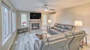 A modern living room with a fireplace, leather sofa, and a ceiling fan. - Spacious Kent Home: Great for Large Families! (Kent)