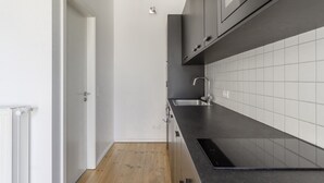 Una cocina moderna con encimera negra, salpicadero blanco de azulejos y un lavabo de acero inoxidable.