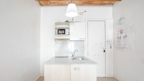 Una cocina pequeña con microondas, un lavabo y un armario blanco.