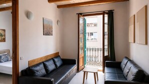 Una habitación con dos sofás de cuero negro, una mesita de madera y un balcón con barandilla de metal.