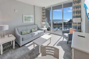 A modern hotel room with a balcony, a sofa, a coffee table, a desk, and a chair. - Direct Oceanfront with Nice Decor, Modern Low Floor (North Myrtle Beach)