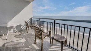 A balcony with a view of the beach, featuring a table and two chairs. - Direct View Centrally located Oceanfront Boardwalk (Myrtle Beach)