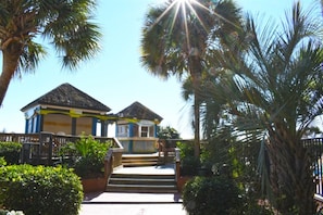 Guests can relax in a thatched-roof bungalow surrounded by lush greenery and palm trees.