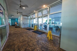A hotel lobby with a patterned floor, large windows, and a caution sign.