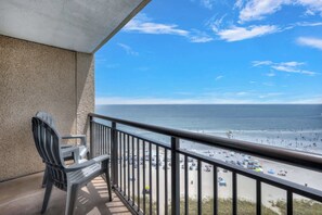 Een balkon met uitzicht op strand en zee.