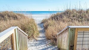 A sandy beach path leading to the ocean, surrounded by tall grasses and wooden structures. - Newest at Beach Cove,Updated Ocean Front,Low Floor (North Myrtle Beach)