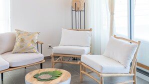 Un salon moderne agrémenté d’un lustre en rotin, de canapés blancs et d’une table basse ronde ornée d’un motif en forme de feuille.