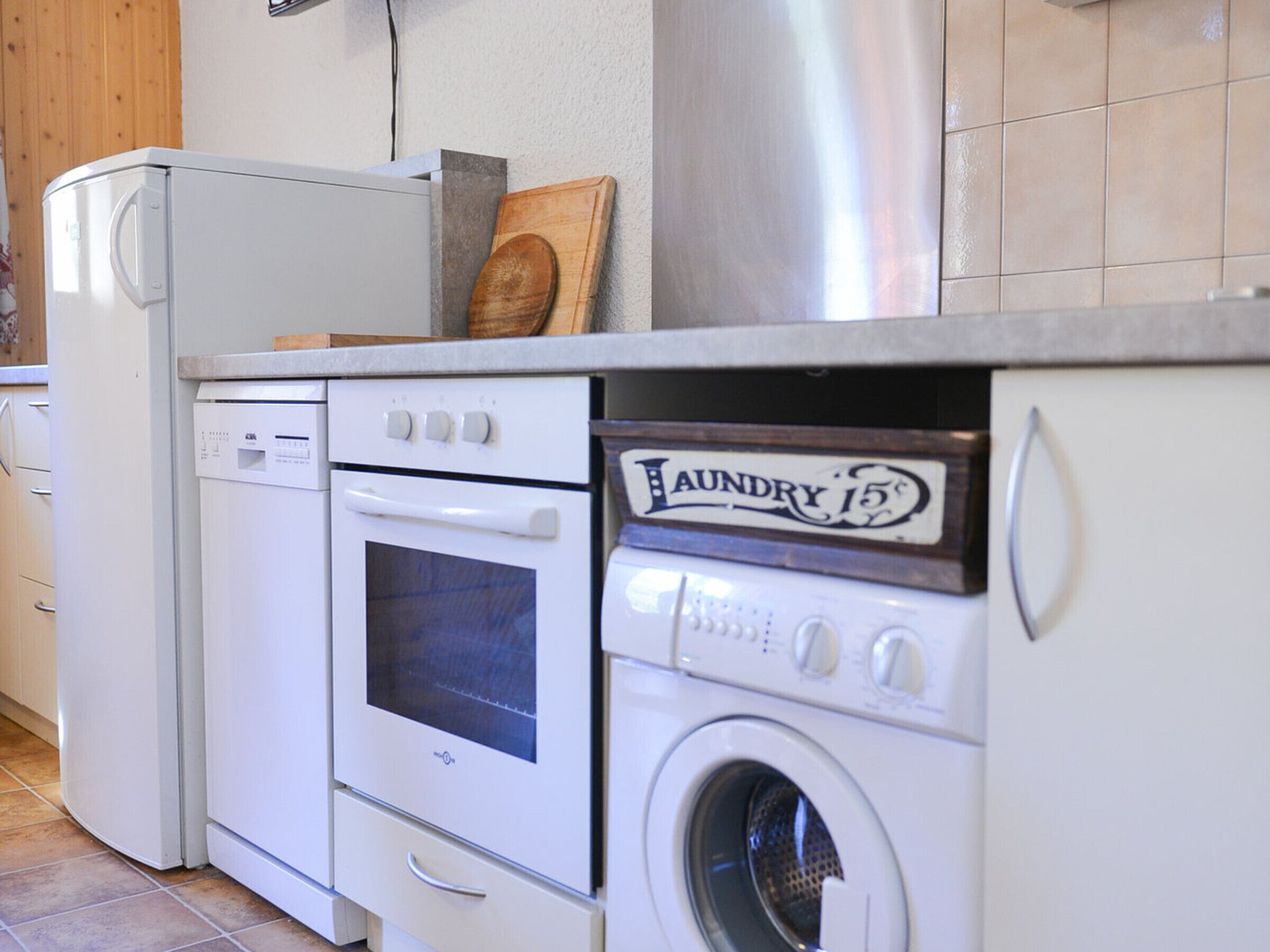 Une cuisine compacte équipée d’un réfrigérateur, d’un four et d’un lave-linge.