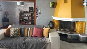 A living room with a white sofa, a fireplace, a bookshelf, and a brick wall. - Comfortable apartment in alsatian house (Oberbronn)