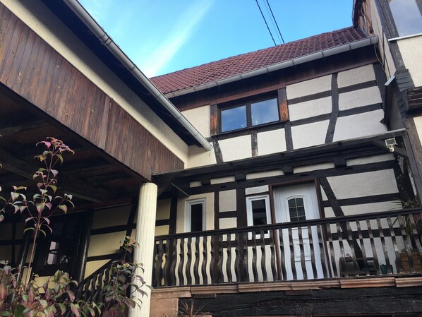 A traditional half-timbered house with a balcony and a wooden staircase.