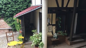 A wooden deck with yellow chairs, a potted plant, and a small table. - Comfortable apartment in alsatian house (Oberbronn)