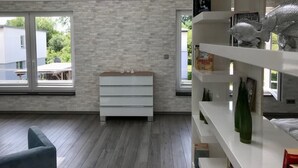 Un salon moderne avec un meuble blanc, une bibliothèque et une grande fenêtre.