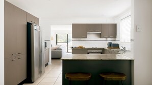 Una cocina moderna con una isla central, electrodomésticos integrados y vistas al salón.