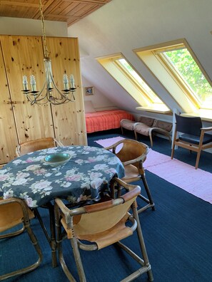 Un coin repas avec une table ronde recouverte d’une nappe à motifs floraux, entourée de chaises en bois.
