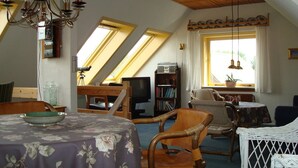 Acogedor dormitorio en ático con una mesa de comedor, sillas, un televisor y una estantería.