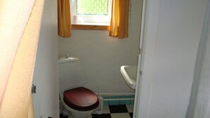 Une petite salle de bain compacte, équipée de toilettes et d’un lavabo.