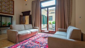 A living room with two sofas, a patterned rug, and a large window with curtains.