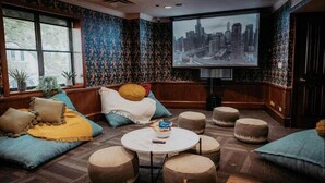 A cozy room with a large screen, comfortable seating, and a cityscape view. - Selina Chicago (Chicago)
