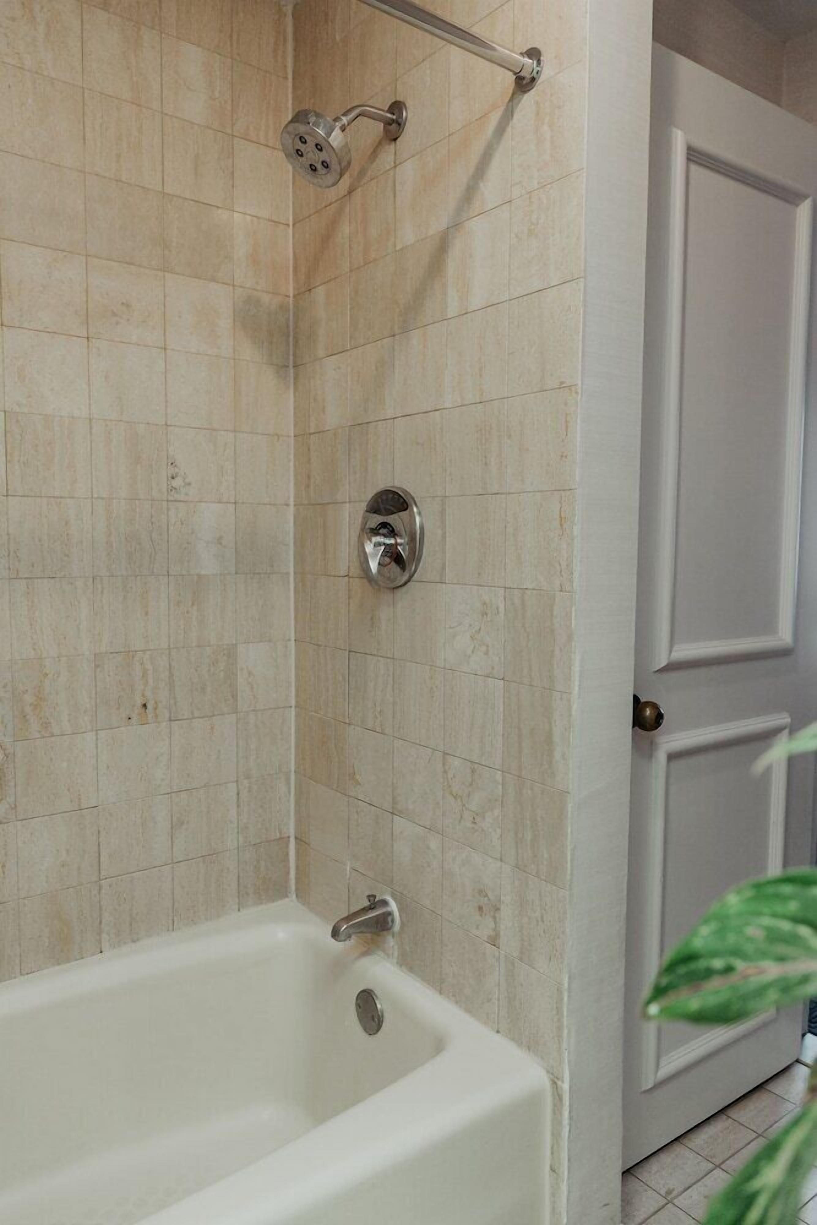 Un baño con bañera, ducha y puerta.