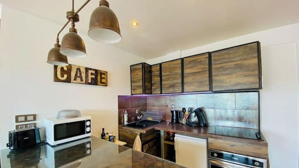 Een moderne keuken met een centraal eiland, een magnetron, een koffiezetapparaat en een fornuis.