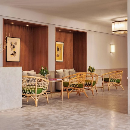 A lobby with a reception desk, wicker chairs, wooden panel walls, and framed artwork.