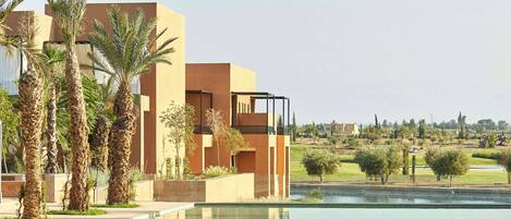 Un edificio moderno con piscina, palme e cielo sereno.