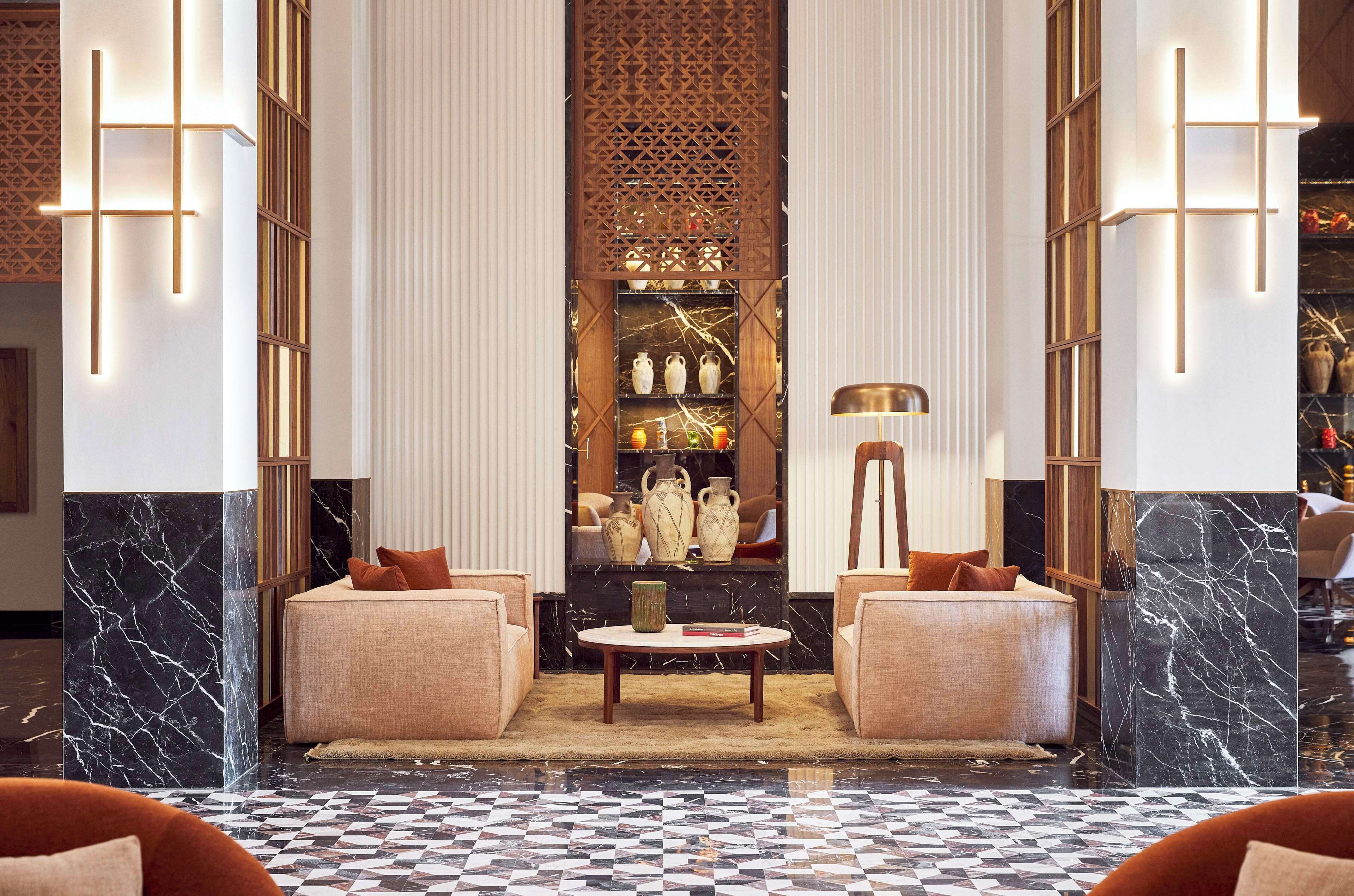 A lobby with a checkered floor, two sofas, a coffee table, and a decorative wall with shelves.