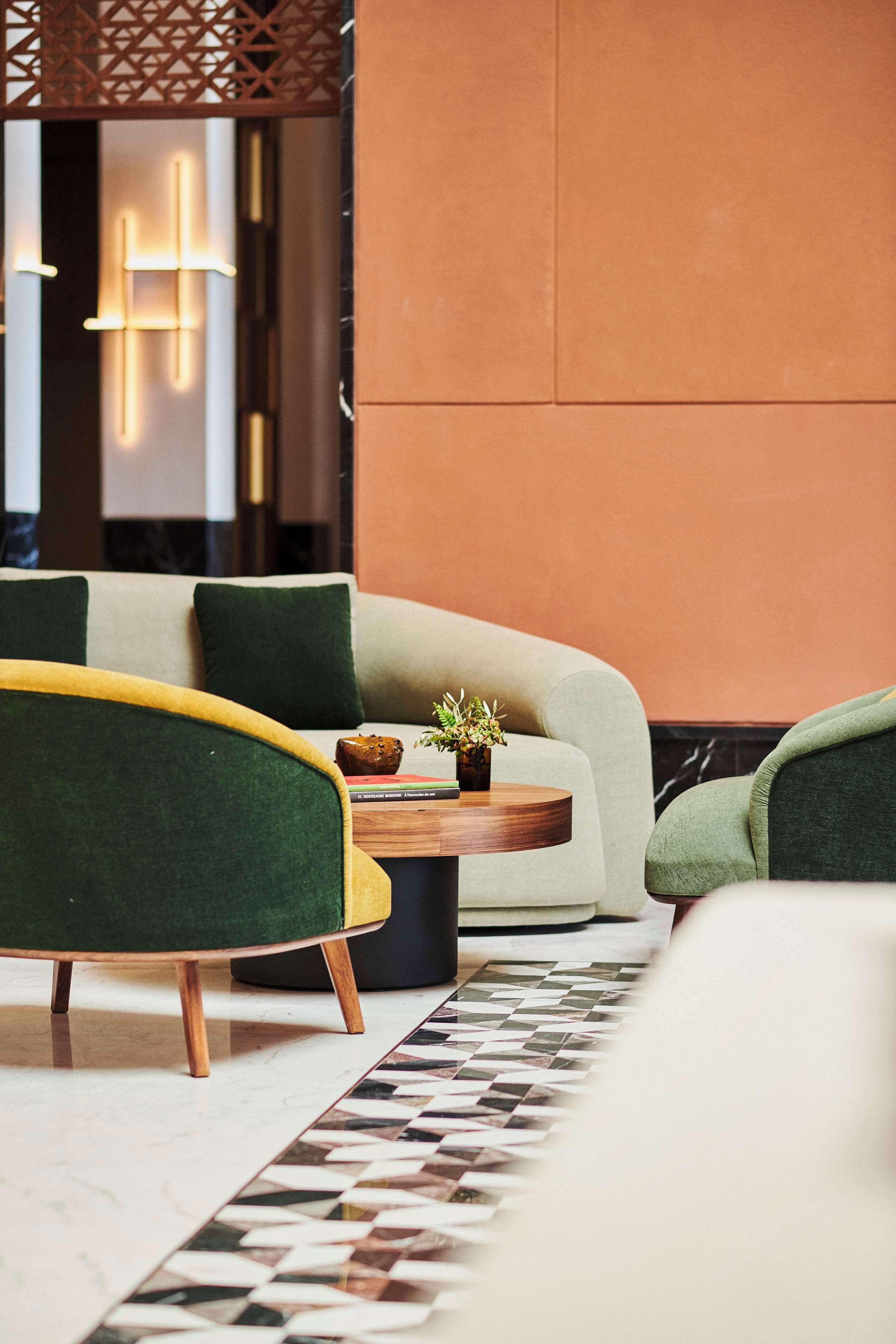 A modern living room with a sofa, armchairs, a coffee table, and a decorative plant.