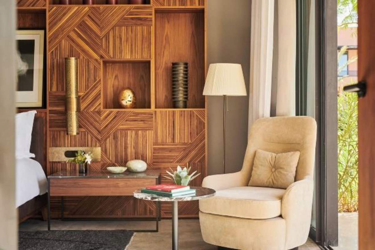 A modern living room with a wooden wall panel, a beige armchair, a small round coffee table, and a floor lamp.