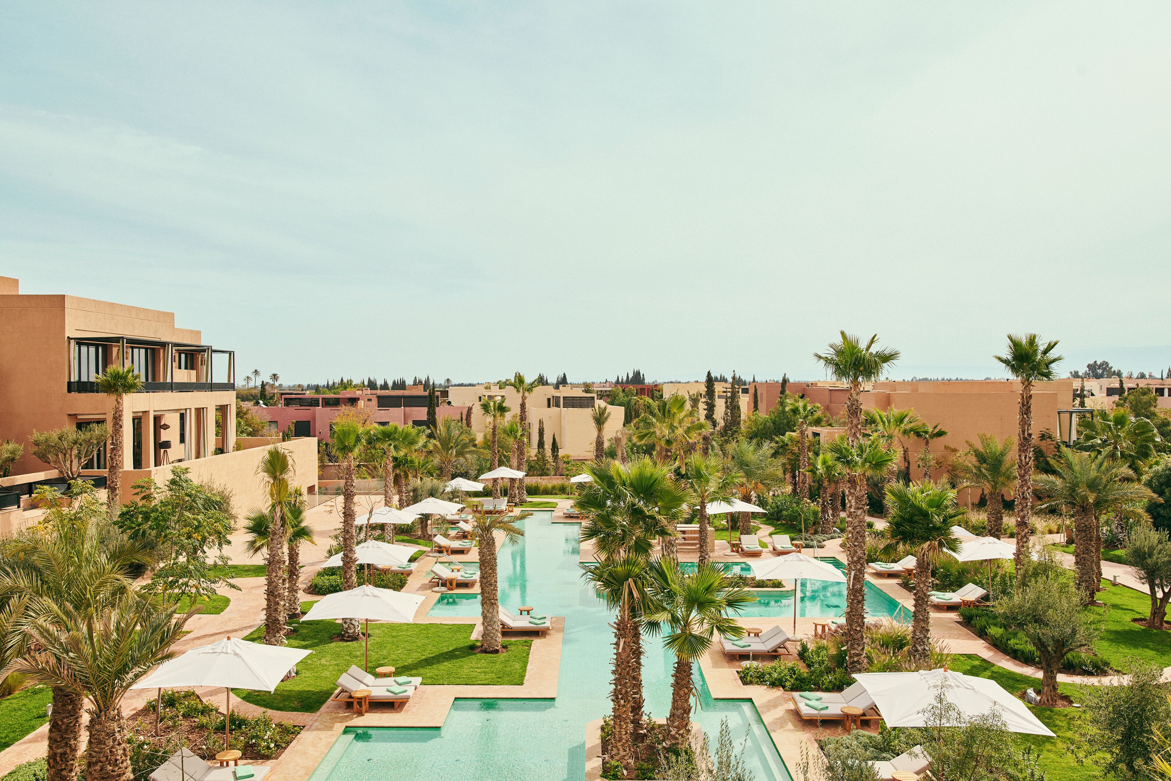 Un resort con varias piscinas, palmeras y zonas de descanso.