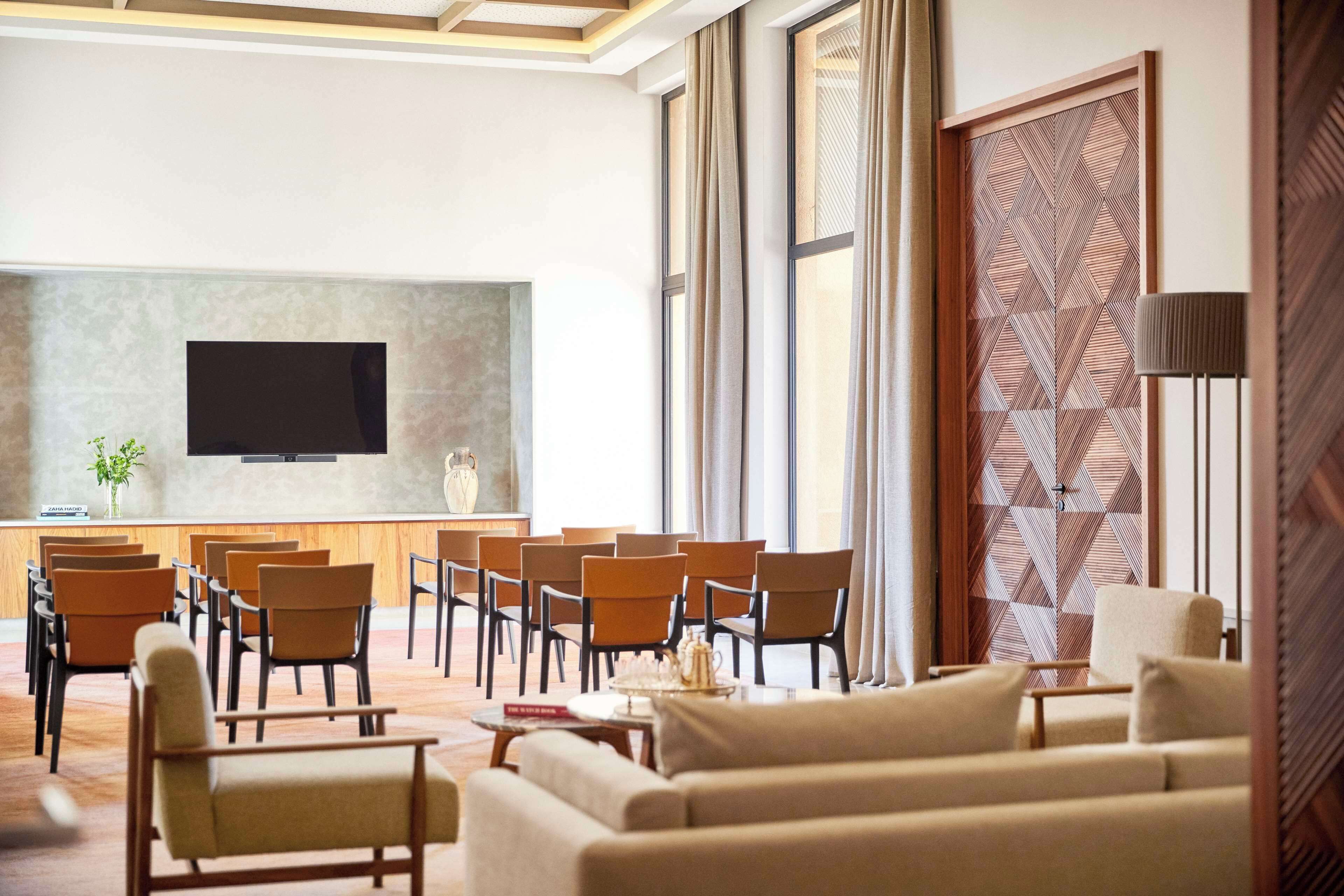 Un hall d’hôtel doté d’un espace salon, d’un téléviseur à écran plat fixé au mur et d’une porte à motifs.