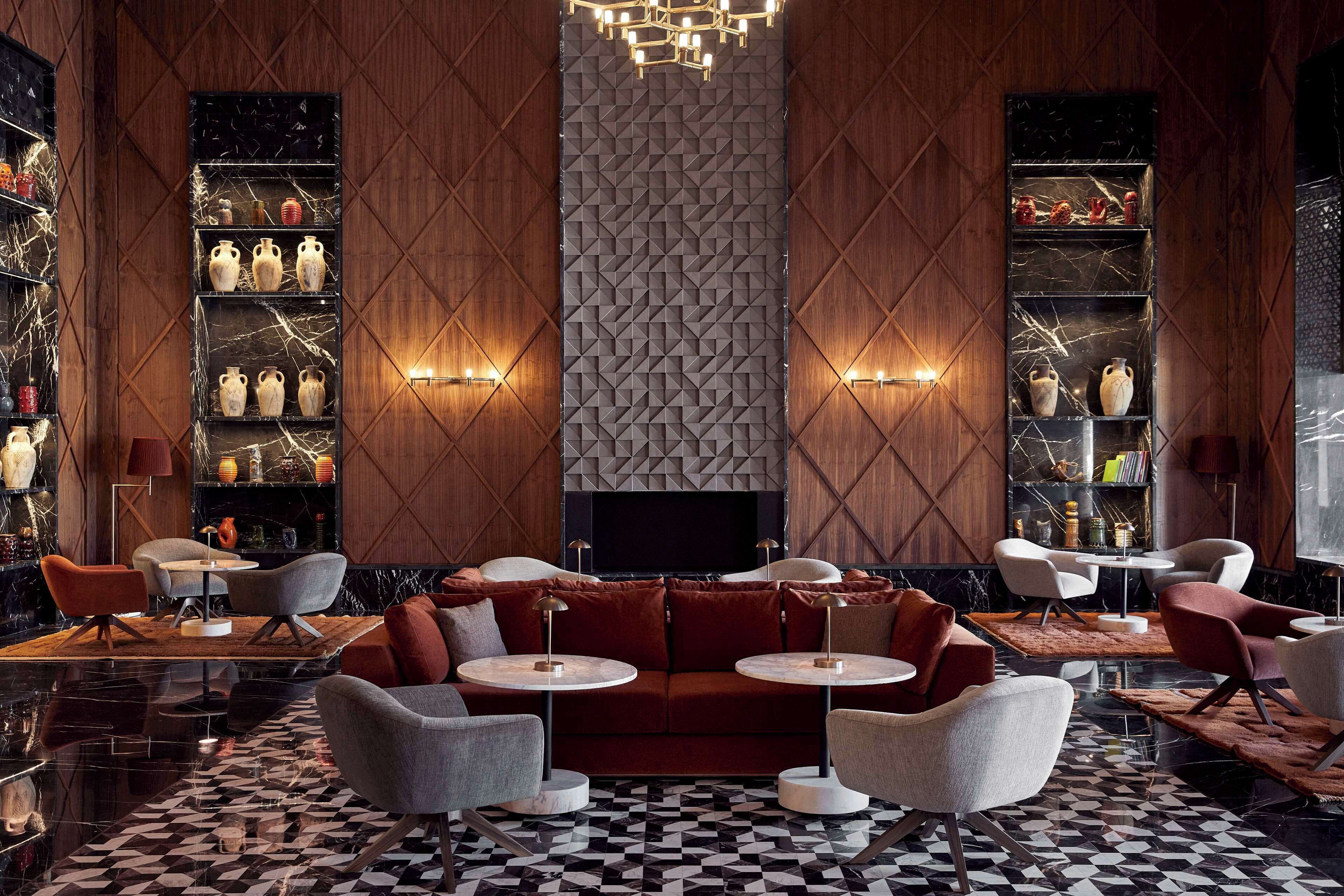 A modern lobby with a checkered floor, a central seating area, and shelves with decorative items.
