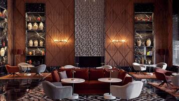 A modern lobby with a checkered floor, a central seating area, and shelves with decorative items.