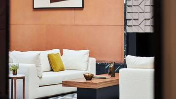 A modern living room with a white sofa, a yellow pillow, a coffee table, and a large abstract painting on the wall.
