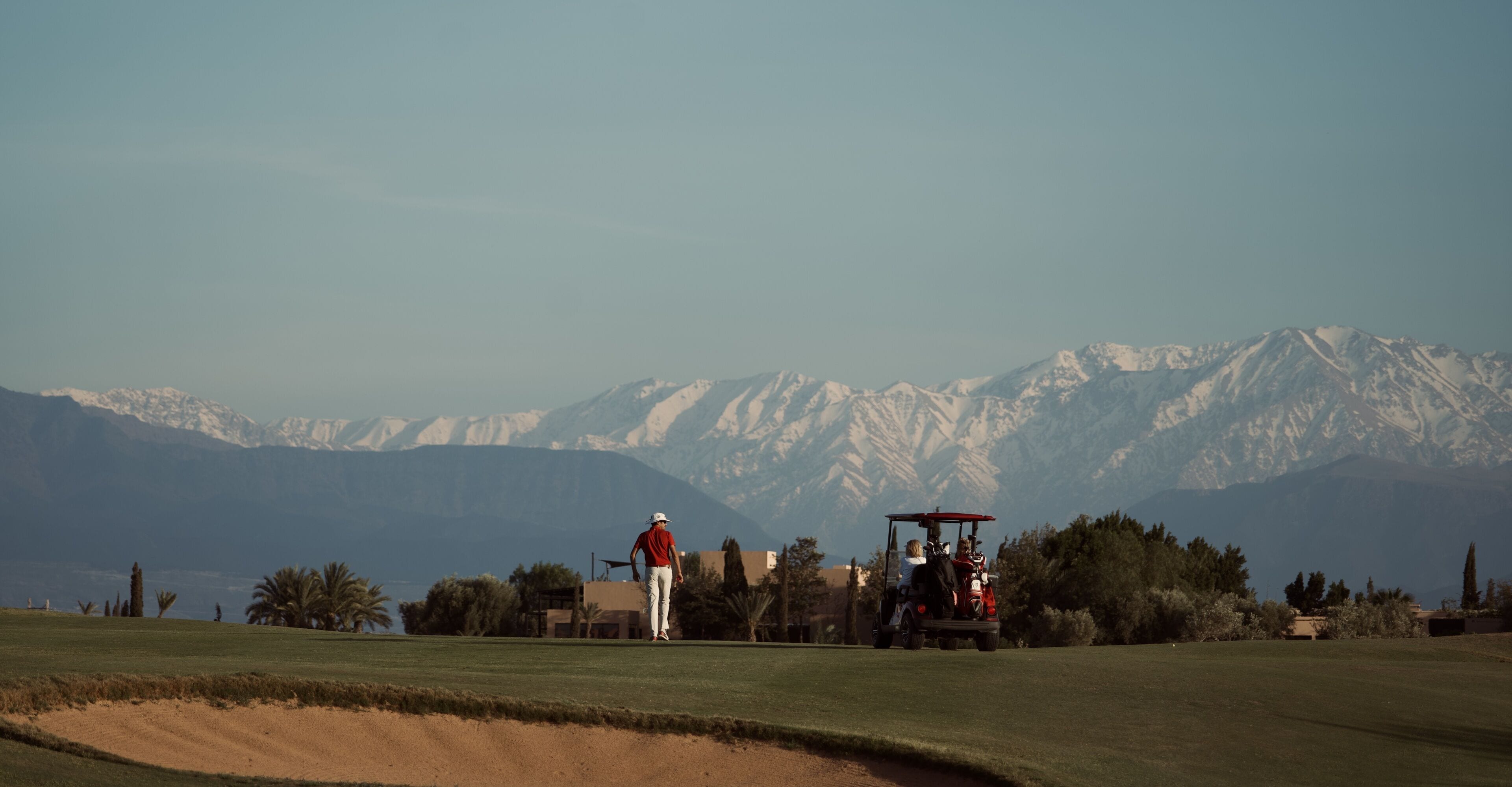 Um campo de golfe com montanhas ao fundo.